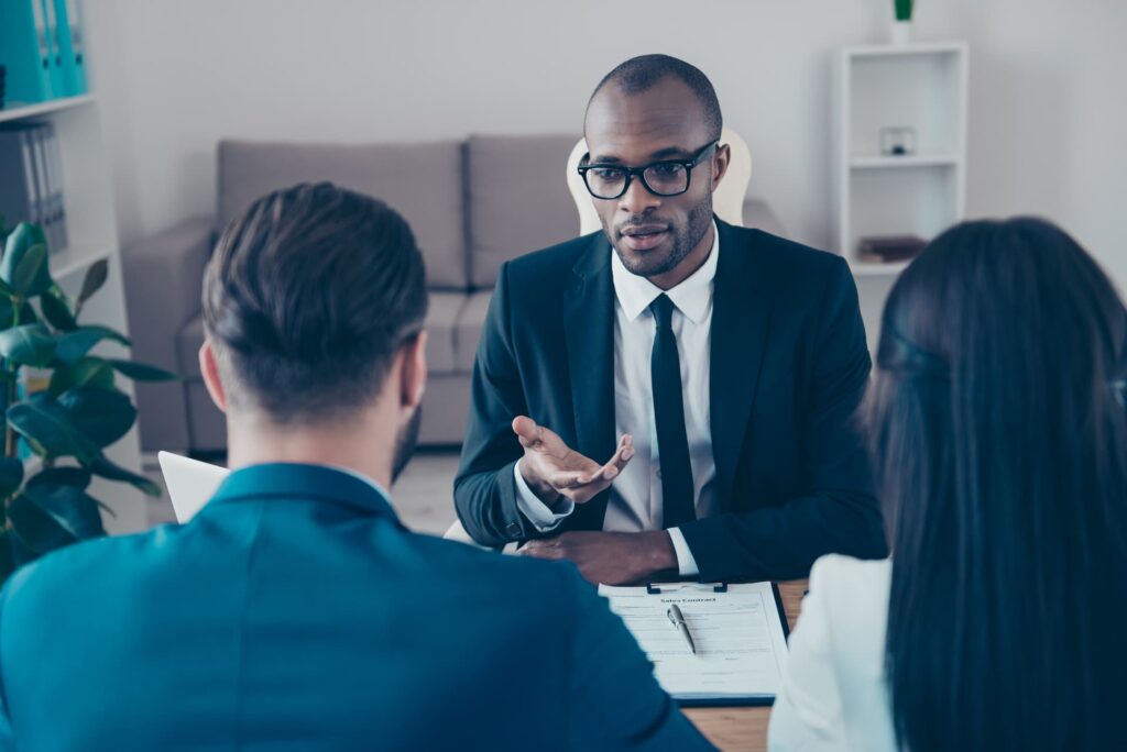 Man explaining something to couple seated at a table